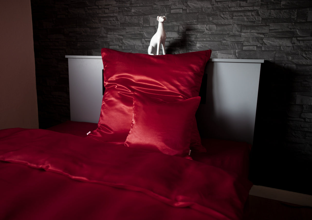 Karmin-Rote Glanz Satin Bettwaesche, dekoriert in einem dunkelgrauen Holzbett.