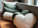 Auf einer Esszimmerbank liegen zwei Herz-Kissen aus Cord-Samt in den Farben bamboo-gruen und kreide-beige.